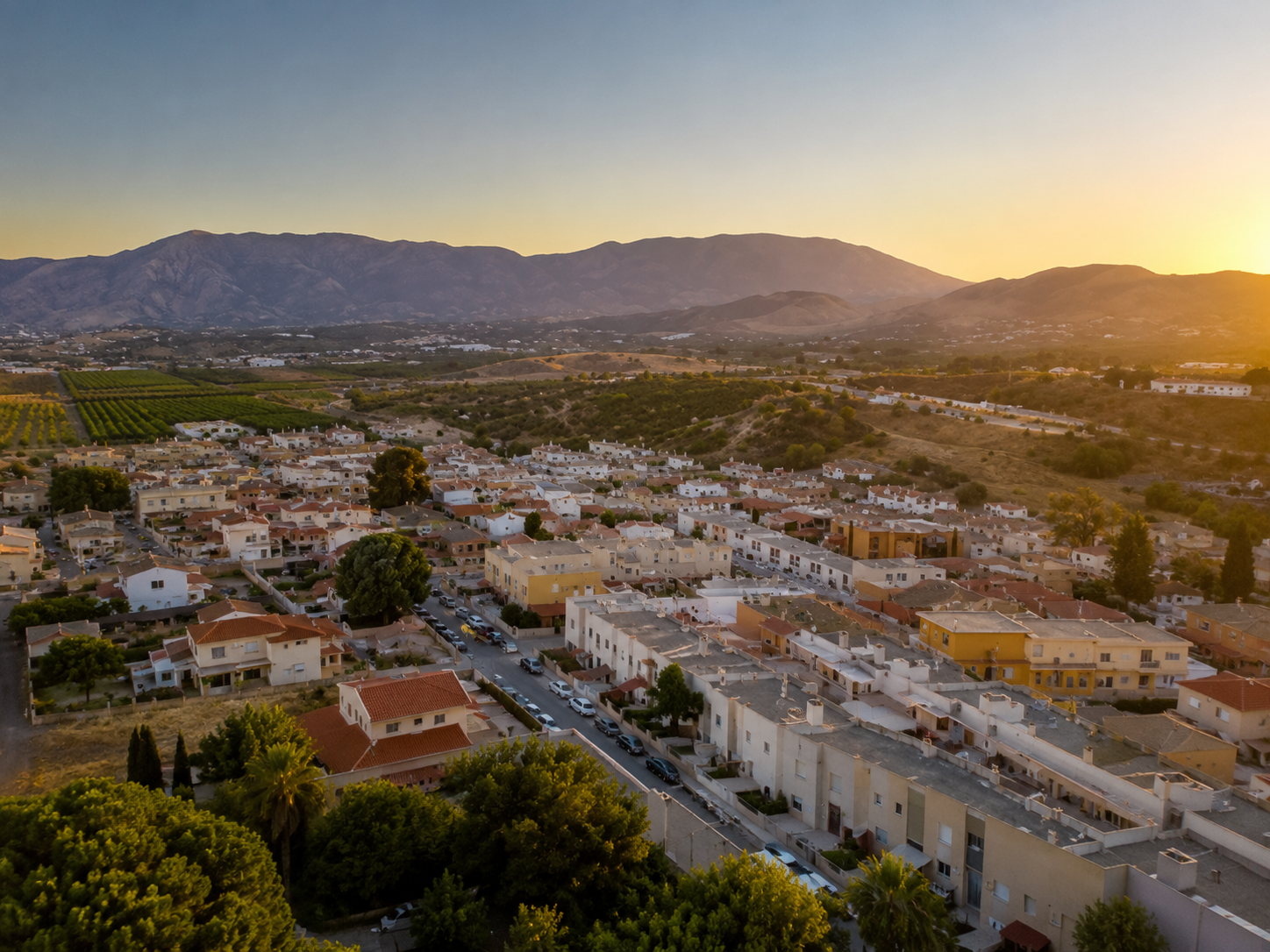 Vista aérea de Campanillas con las casas del barrio y la sierra al fondo al atardecer